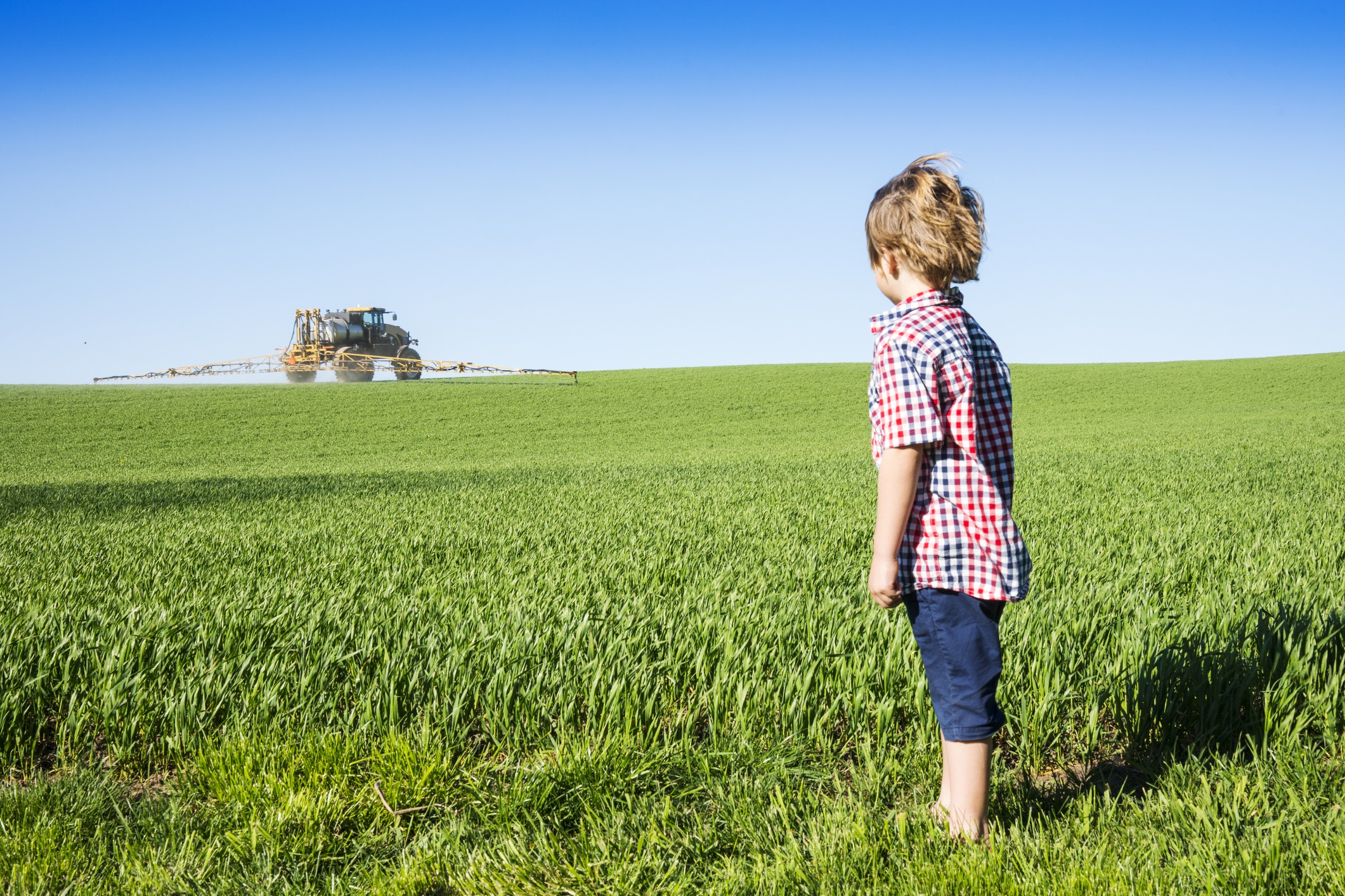 Farm kid looking at a crop sprayer