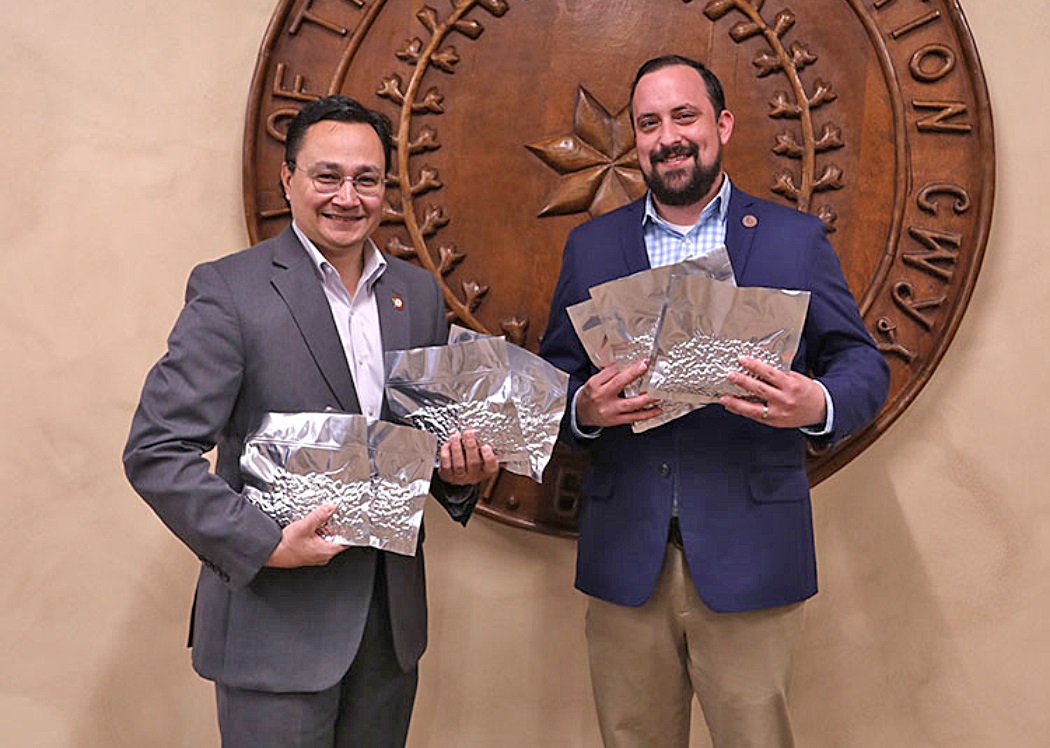 Two men holding bags of seed